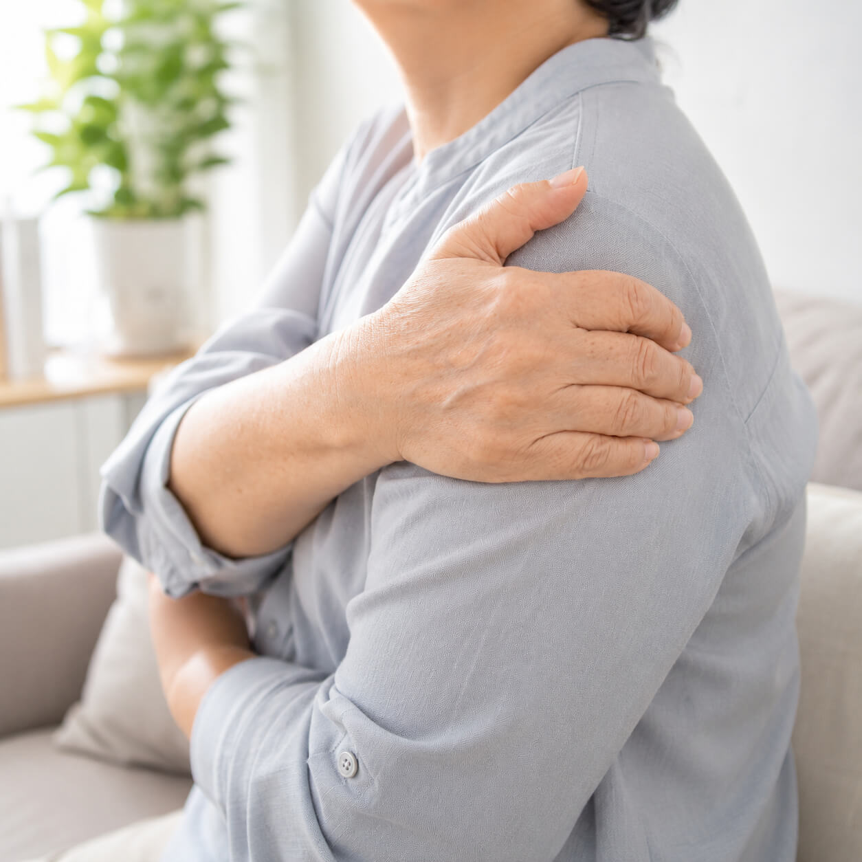Patient holding shoulder due to shoulder arthritis pain at home
